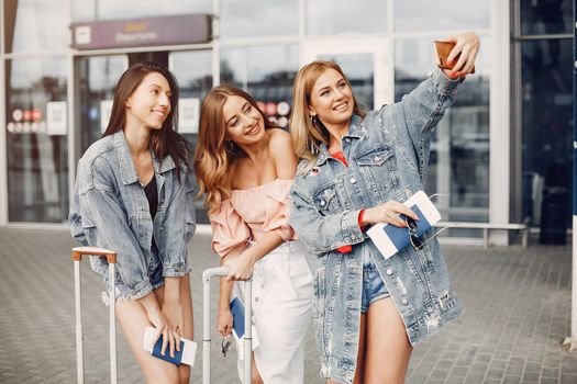 Girls at the airport. Friends with suitcases. Ladies using the phone