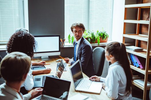 Project presentation at meeting room looking at white screen colleagues gather discuss financial statistics together, multiracial coworkers cooperating working together at office meeting.