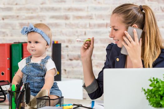 Family Business - telecommute Businesswoman and mother with kid is making a phone call. At the workplace, together with a small child