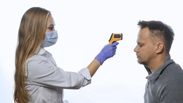 Testing employee's or patients body temperature using a non-contact thermometer nurse wearing a medical mask. Sad man unhappy of disease. Isolated on white background.