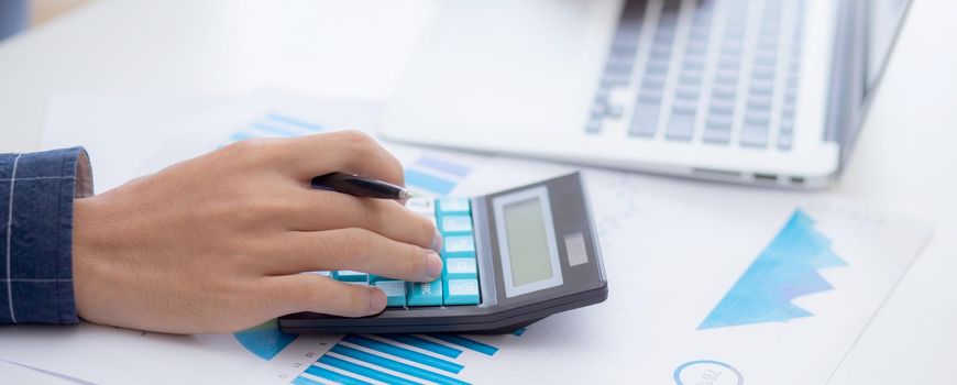 Hand of young asian business man working using calculator for planning accountant, graph for finance and report statistics, investment and profit of income, businessman analyzing with chart.
