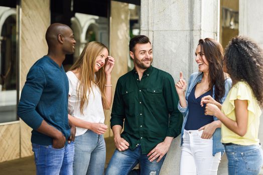 Multi-ethnic group of young people having fun together outdoors in urban background. group of beautiful women and men laughing together