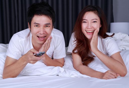 laughing couple watching movie on bed in the bedroom
