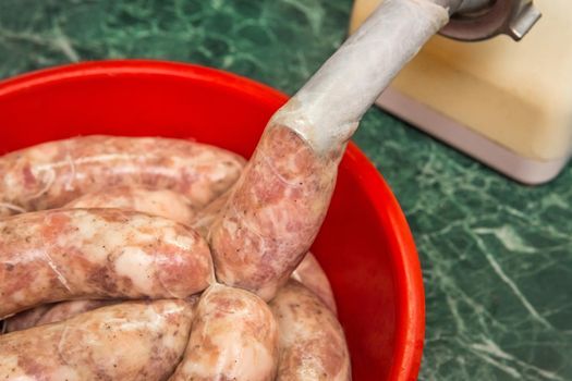 Cooking sausages from raw minced meat using a natural shell and meat grinder at home close up.