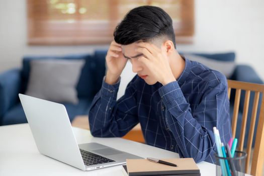 Young asian business man headache during working on laptop computer with deadline on desk at home, businessman with failure exhausted and tired, stress and worried, frustrated and unsuccessful.