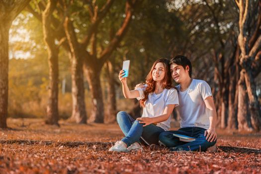 young couple using mobile phone taking a selfie in the park