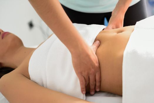 Hands massaging female abdomen.Therapist applying pressure on belly. Woman receiving massage at spa salon