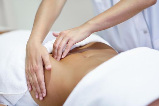 Female patient is receiving treatment by professional osteopathy therapist. Woman receiving a belly massage at spa salon