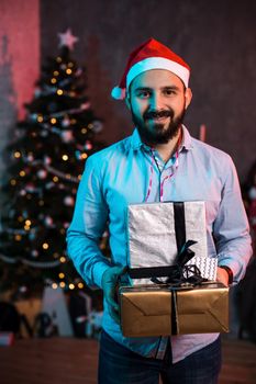 Christmas, x-mas, New year, winter, happiness concept - smiling man in santa helper hat with gift boxes. Funny people. Christmas party at home