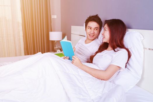 young couple reading a book on bed in the bedroom