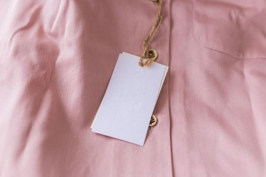 Close-up blank tag label on pink shirt. Copy space