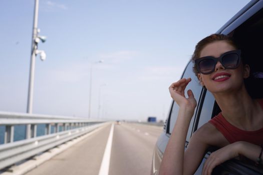 a woman is driving in a car on the road and looking out of the window. High quality photo