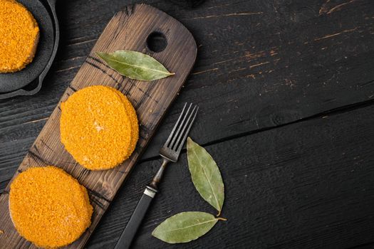 Breaded fish patties set, on black wooden table background, top view flat lay, with copy space for text