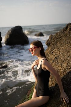 woman in swimsuit sunglasses ocean rocks posing. High quality photo