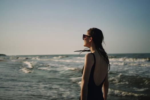 woman in black swimsuit walking on the beach ocean summer. High quality photo