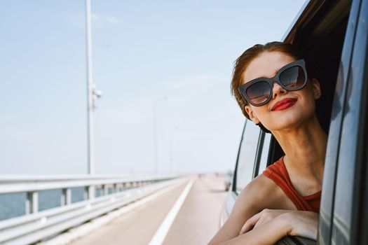 a woman is driving in a car on the road and looking out of the window. High quality photo