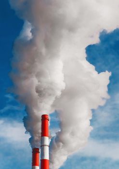 Environmental pollution, environmental problem, smoke from the chimney of an industrial plant or thermal power plant on a background of blue sky with clouds.