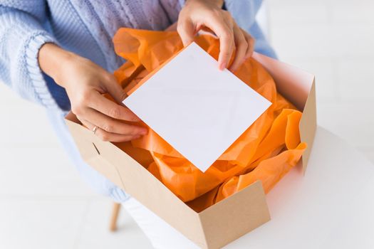 Delivery and fashion concept - Woman sitting on sofa at home opening online clothing purchase
