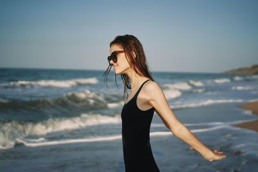 pretty woman in black swimsuit posing sun walking on the beach. High quality photo