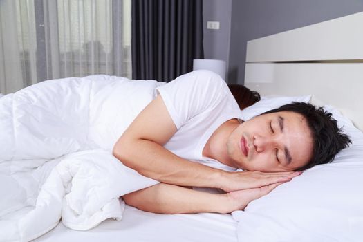 young man sleeping with his wife in a comfortable bed at home