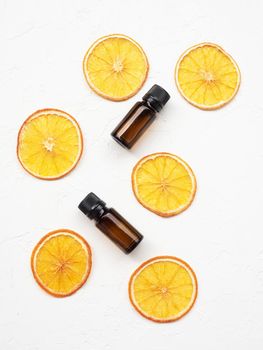 Eco-friendly cosmetics and aromatherapy concept. Top view of organic essential oil with slices of dried orange. Natural cosmetics product. Glass containers with liquid.