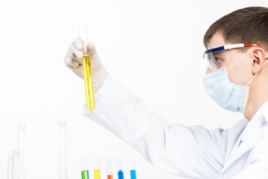 Laboratory technician in safety mask and latex gloves checking liquid sample in test tube. Virology laboratory research and development. Medicaments and vaccine testing. Pharmacology industry concept