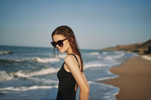 pretty woman in black swimsuit posing sun walking on the beach. High quality photo