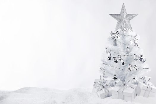 Beautiful white Christmas tree on snow decorated with balls and star isolated on white background
