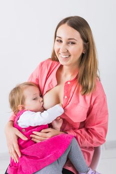 Mother breastfeeding baby in her arms at home. Young woman nursing and feeding baby. Concept of lactation infant.