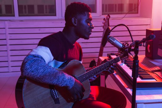 African american professional musician recording guitar in digital studio at home, music production technology concept