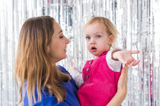 Childhood, holidays and family concept - Mother kissing baby daughter on shiny background. Close-up.