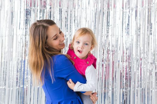 Childhood, holidays and family concept - Mother kissing baby daughter on shiny background. Close-up.