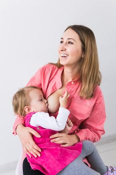 Young beautiful mother, breastfeeding her baby girl. Mom breastfeeding infant.