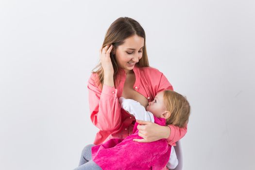 Mother breastfeeding baby in her arms at home. Young woman nursing and feeding baby. Concept of lactation infant.