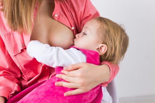 Lactation and motherhood concept - Young beautiful mother holding breastfeeding baby sitting on chair