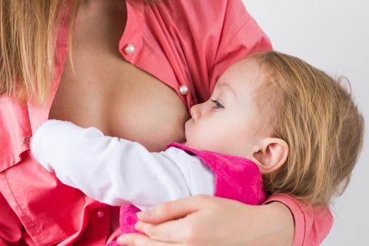 Mother breastfeeding baby in her arms at home. Young woman nursing and feeding baby. Concept of lactation infant.