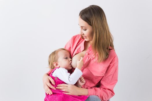 Lactation and motherhood concept - Young beautiful mother holding breastfeeding baby sitting on chair