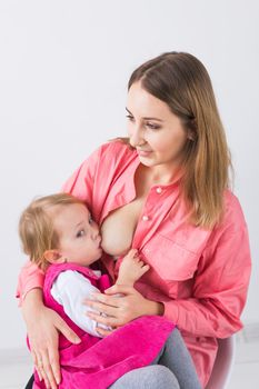 Mother breastfeeding baby in her arms at home. Young woman nursing and feeding baby. Concept of lactation infant.