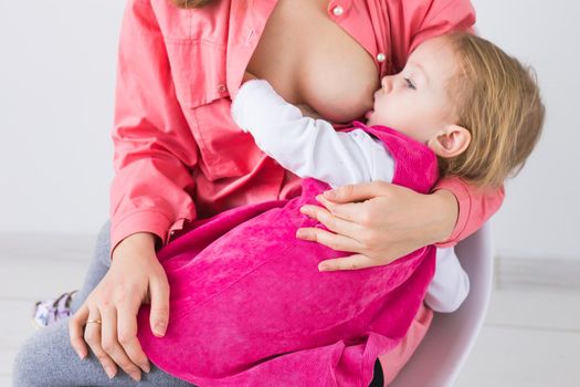 Mother breastfeeding baby in her arms at home. Young woman nursing and feeding baby. Concept of lactation infant.