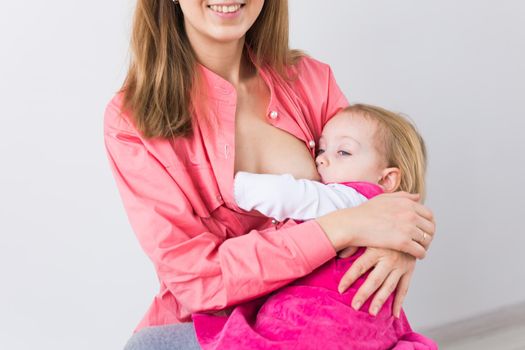 Mother breastfeeding baby in her arms at home. Young woman nursing and feeding baby. Concept of lactation infant.