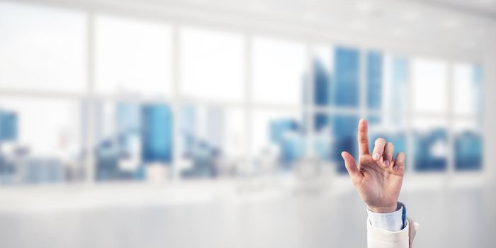 Close of businesswoman hand touching screen with finger and office at background