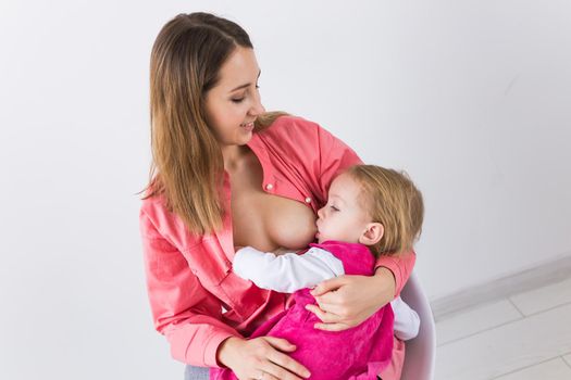 Young beautiful mother, breastfeeding her baby girl. Mom breastfeeding infant.