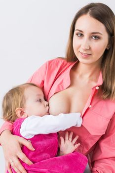 Mother breastfeeding baby in her arms at home. Young woman nursing and feeding baby. Concept of lactation infant.