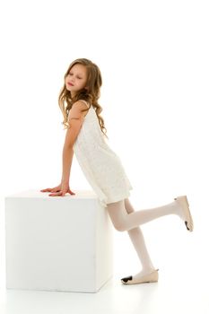 Front View Portrait of Beautiful Girl in Elegant White Lace Dress Standing and Leaning on Cube in Studio, Long Haired Girl Wearing Fashionable Stylish Clothes Posing Against White Background