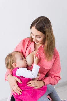 Mother breastfeeding baby in her arms at home. Young woman nursing and feeding baby. Concept of lactation infant.