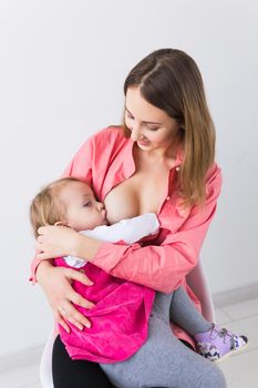 Mother breastfeeding baby in her arms at home. Young woman nursing and feeding baby. Concept of lactation infant.