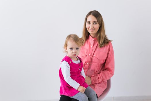 Childhood and family concept - Mother holds baby daughter on white background with copy space.