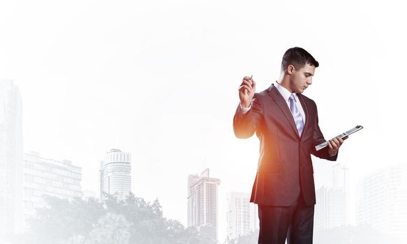Businessman looking into documents and pointing away on white background. Front view of standing man in business suit and tie. Successful business person in formal wear gesturing with raised hand