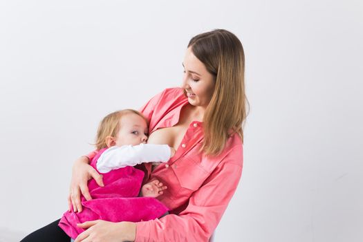 Mother breastfeeding baby in her arms at home. Young woman nursing and feeding baby. Concept of lactation infant.