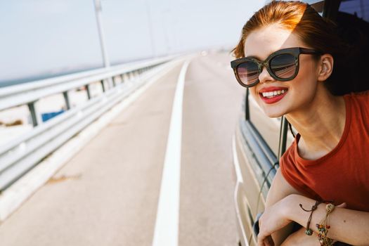 cheerful woman peeking out of the car window trip adventure lifestyle. High quality photo